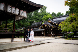 京都・今宮神社の社殿を背景に並ぶ白無垢の新婦と紋付袴の新郎